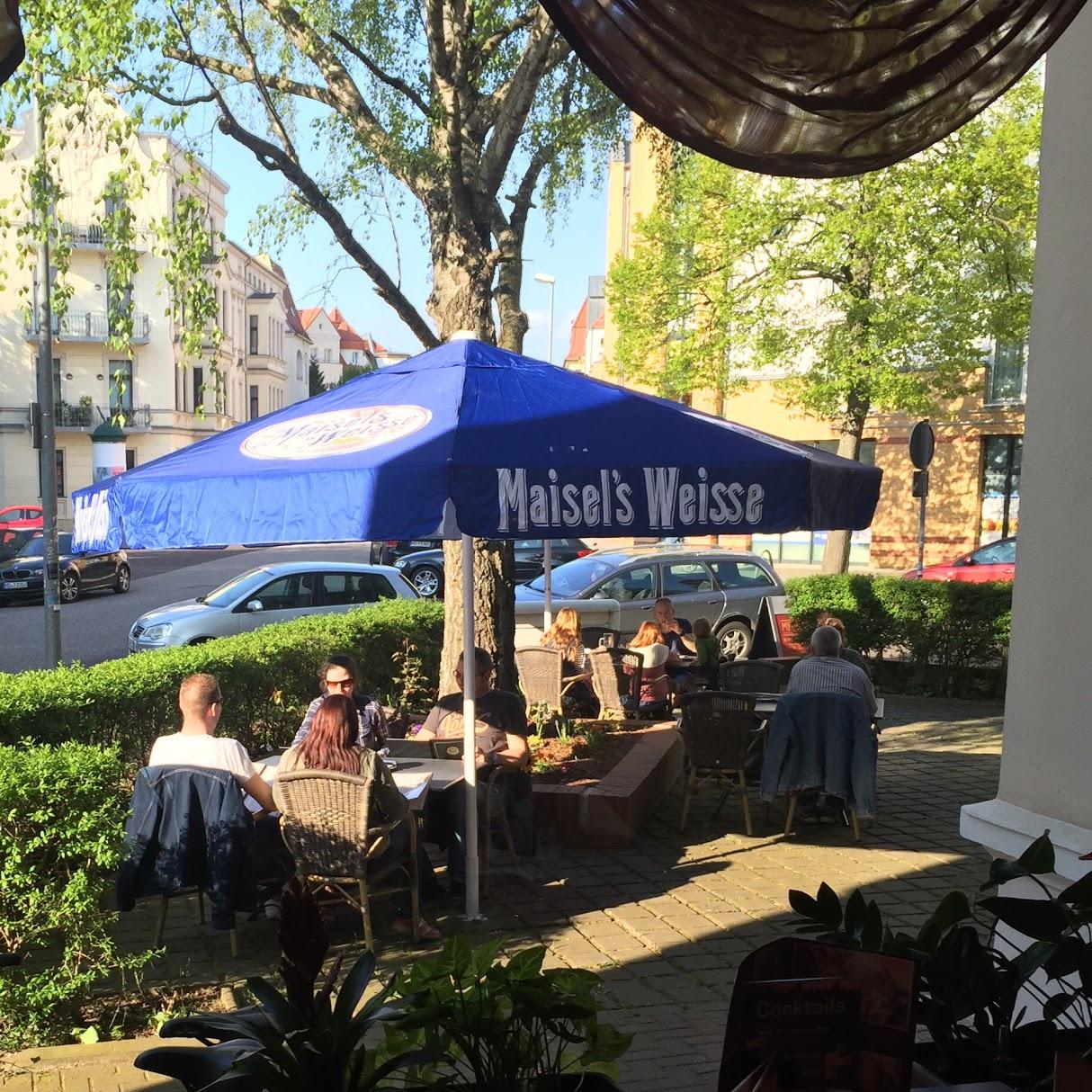 Sonnenbeschienene Terrasse von Mythos mit blauen Sonnenschirmen