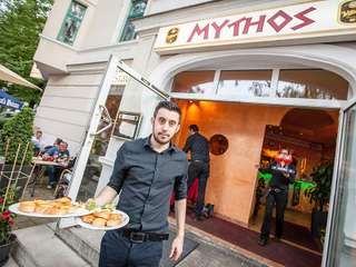 Kellner von Mythos serviert griechische Vorspeisen vor dem Restauranteingang